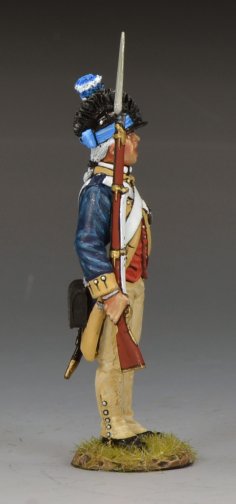 A military miniature figurine of a Revolutionary War soldier stands at attention, wearing a blue and red uniform with tan trousers, white crossbelts, and a tall black hat with a blue plume, holding a musket upright by his side.