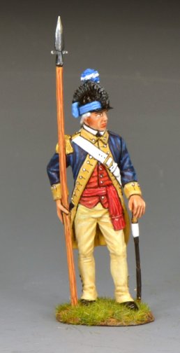 A military miniature figurine dressed in an 18th-century military uniform with a blue coat, red vest, yellow trousers, and a black hat, holding a spear, stands on a small grassy base against a plain background.
