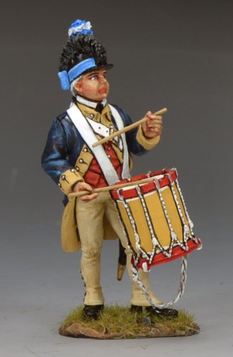A painted military miniature figure of a historical soldier in uniform, playing a drum. The figure stands on a small grassy base and wears a dark blue coat, cream pants, and a tall hat with a blue plume.