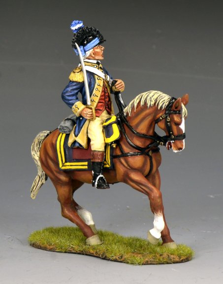 A painted miniature figurine of a soldier in an 18th-century uniform riding a brown horse with a white mane and tail, set on a grassy base. The soldier holds a sword and wears a blue jacket with yellow trim.