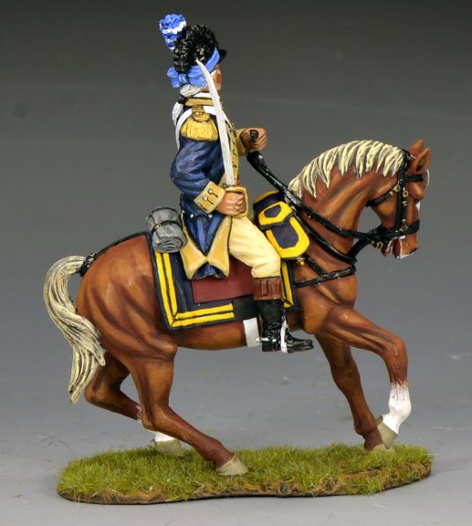 A painted toy soldier figurine of a soldier in an 18th-century uniform riding a brown horse with a white mane and tail, set on a grassy base. The soldier holds a sword and wears a blue jacket with yellow trim.