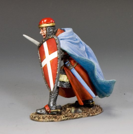 A painted military miniature of a medieval knight in chainmail, red tunic, and red helmet, holding a sword and a red shield with a white cross, and wearing a blue cape, kneeling on one knee on a textured base.
