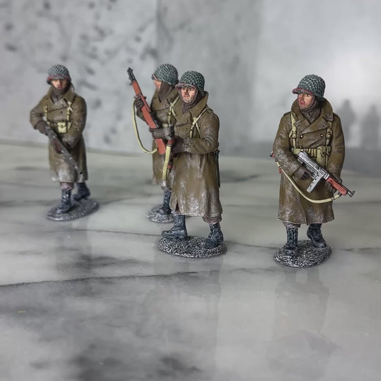 360 view of King & Country BBA100 four-figure set of a U.S. infantry patrol advancing through snow in winter overcoats — an NCO with a Thompson, two riflemen with M1 Garands, and a BAR gunner.