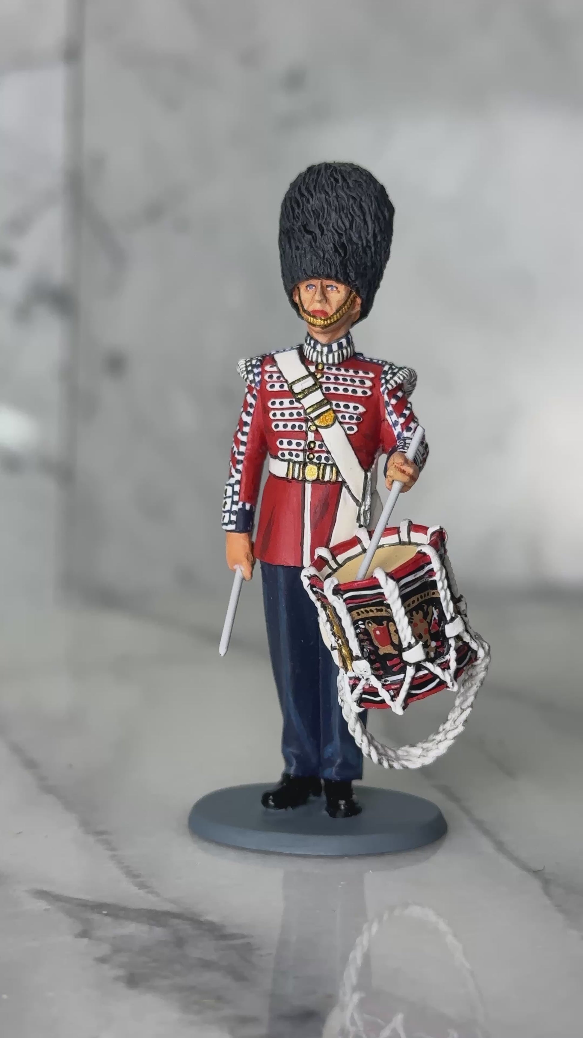 360 view of military miniature King & Country Scots Guards drummer — 1/30 scale matte-painted figure in scarlet ceremonial tunic, bearskin cap, with side drum. Catalog CE120.