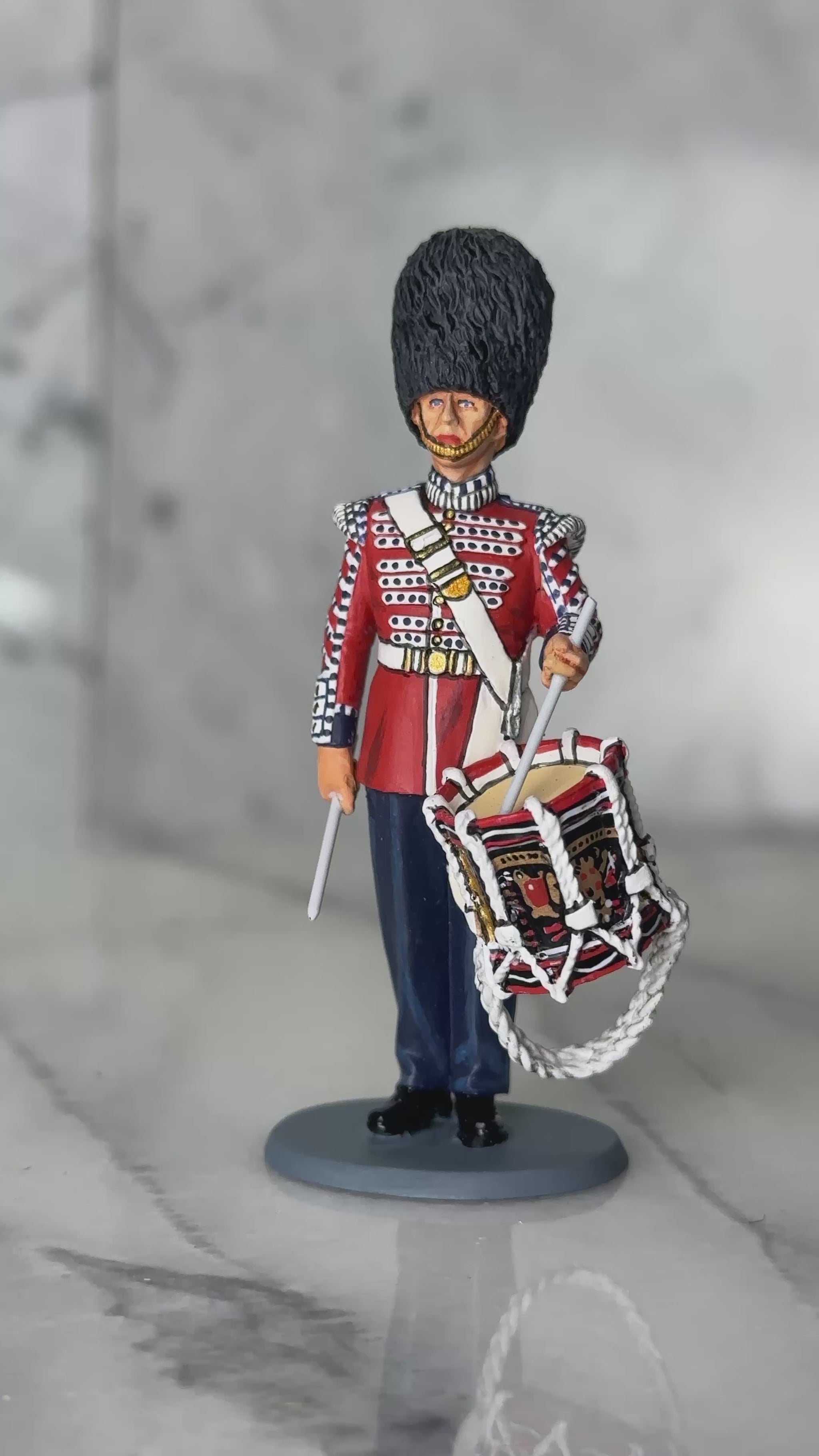 360 view of military miniature King & Country Scots Guards drummer — 1/30 scale matte-painted figure in scarlet ceremonial tunic, bearskin cap, with side drum. Catalog CE120.