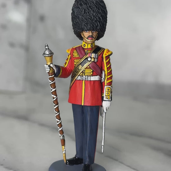 360 view of toy soldier King & Country Scots Guards Drum Major — 1/30 scale matte-painted figure in ceremonial scarlet with gold lace, red sash, and bearskin cap, holding mace. Catalog CE122.
