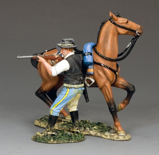 A painted figurine of a man in a black hat, vest, and blue-striped pants aiming a rifle while standing beside a brown horse equipped with a blue bedroll and black reins, both on a textured base.