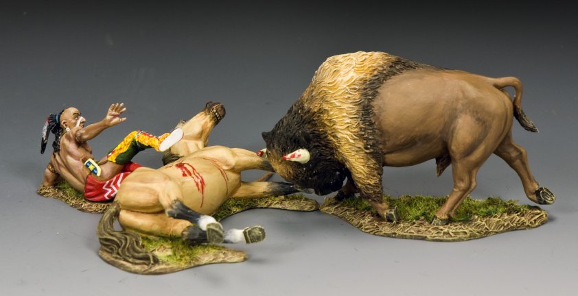 A toy soldier painted figurine scene shows a bison attacking a fallen horse while a Native American man in colorful clothing and a feather headdress falls backward, appearing startled or injured, on a grassy base.