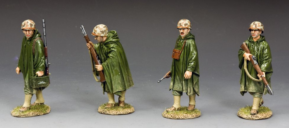 Four painted miniature marine figures in green uniforms with weapons on a gray background