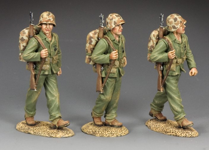 Three toy soldiers in green uniforms with backpacks and rifles on a gray background