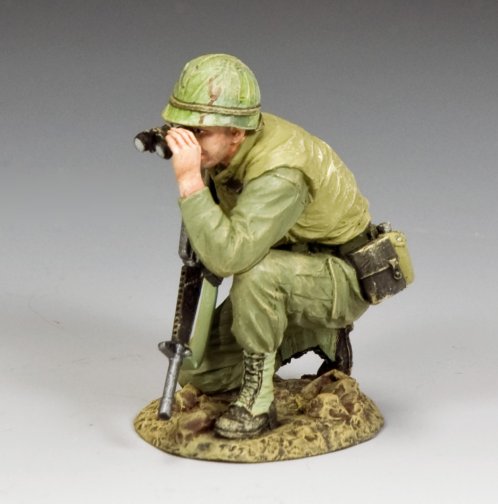 A miniature figurine of a soldier in green uniform and helmet, crouching on one knee, looking through binoculars with a rifle resting on the ground.