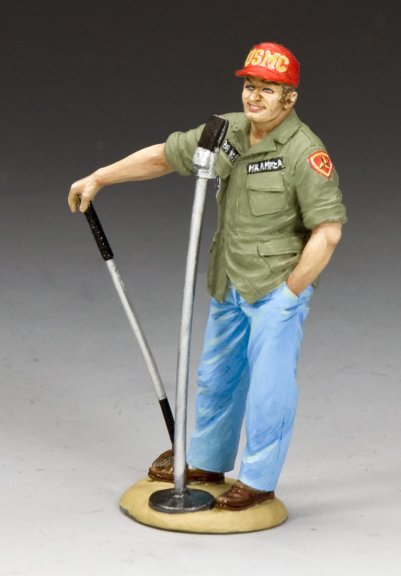 Figurine of a soldier in uniform with a red cap, holding a golf club on a gray background