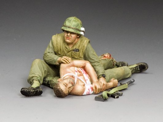 Taking Care of a Buddy. Military miniature Model figure of a soldier tending to an injured person on a gray background