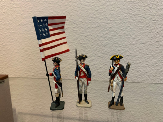 three revolutionary war toy soldiers one with flag