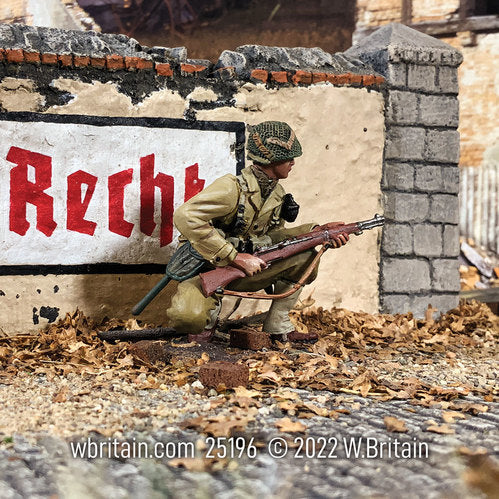 Toy soldier army men U.S. Armored Infantryman Kneeling Alert 1943-45. He is in front of a sign.